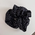 Gros plan du chouchou noir à pois blancs avec une texture de tissu à volants - Noir