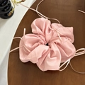 Detalle de un coletero rosa claro con delicados lazos de cinta de seda sobre madera - Rosa