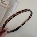 Detailed macro of a slim tortoise shell acetate hair clip with protective black rubber tips - Headband