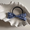 Dettaglio dell'elastico per capelli con fiocco a scacchi blu e bianco su piatto conchiglia - Elastico Capelli Fiocco Quadretti Blu
