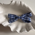 Dettaglio del fermaglio per capelli con fiocco a scacchi blu e bianchi su vassoio bianco - Molletta Fiocco Quadretti Blu