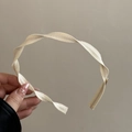 Gros plan d'un serre-tête beige torsadé avec une texture tissée élégante et design en spirale - Blanc