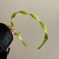 Detailed shot of fluorescent green spiral fabric headband with gold metal ornament - Green