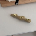 Detail of wavy fabric hair clip with three yellow decorative bows on beige cotton material - Yellow