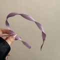 Detail of lavender spiral fabric headband featuring a small round gold logo accent - Light Purple