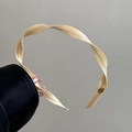 Gros plan d'un serre-tête en tissu beige plissé avec petit logo métallique doré - Abricot