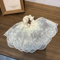 Close-up of double-layered cream lace scrunchie with intricate patterns on wood surface - Off White