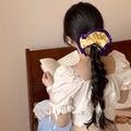Détail d'un chouchou à carreaux jaunes avec dentelle violette sur une longue tresse femme - Carreaux Jaunes (Volant Violet)