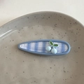 Nahaufnahme einer blau-weiß karierten Haarspange mit 3D-Kirschdekor auf Teller - Kirschblau-Clip - Wassertropfen