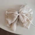 Detail view of cream chiffon bow hair claw with soft pleats and a delicate pearl pendant - Beige