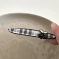 Detailansicht der schwarz-weißen Karo-Haarklammer mit Kirsch-Dekor, in der Hand gehalten - Kirschschwarz-Clip - Gerade