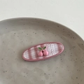 Nahaufnahme der rosa karierten Kirsch-Haarspange mit Spitze auf einem Teller - Kirschrosa-Clip - Oval