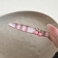 Nahaufnahme einer rosa karierten Stoff-Haarspange mit 3D-Kirsch-Anhänger in der Hand - Kirschrosa-Clip - Gerade