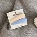 Dettaglio di fermagli per capelli color azzurro e beige su sfondo in maglia grigia - Coppia Blu Crema - Triangolo