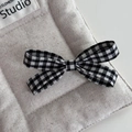 Detailed view of sweet black and white gingham bow hair clip on a soft quilted fabric - Gingham Bow Duckbill Clip / Black