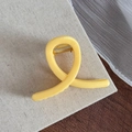 Vue détaillée de la pince à cheveux en résine jaune vif avec ressort en métal doré - Jaune Fromage Forme Torsadée