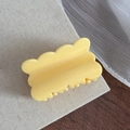 Détail d'une pince à cheveux jaune crème aux bords festonnés sur un fond en lin rustique - Jaune Fromage Rectangle Ondulé