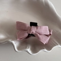 Vista detallada de la pinza para el cabello con lazo de tela rosa en un plato de cerámica - Rosa