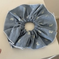 Detail of grey-blue scrunchie featuring white bow patterns and fine stitched edges - Denim Bow