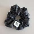 Dettaglio di scrunchie in tessuto a righe grigie con una toppa bianca e testo stampato - Nero (Elastico con Etichetta)
