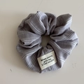 Gros plan d'un chouchou en tissu à rayures grises et blanches avec écusson sur blanc - Gris (Chouchou Étiquette)