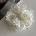 Détail d'un chouchou en dentelle crème avec perles dorées et texture plissée élégante - Blanc