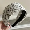 Close-up of wide padded headband featuring black floral patterns on white fabric - White Wide - Vine