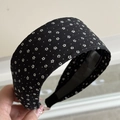Close-up of wide fabric headband with black white polka dots and anti-slip inner strip - Black Wide - Floral
