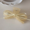 Dettaglio molletta per capelli a fiocco in resina giallo crema su piatto di porcellana - Giallo