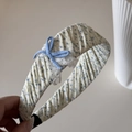 Detail van een bloemenstof hoofdband met blauwe strik en witte kanten rand voor dames - Bloemen Stof Hoofdband / Blauwe Hoofdband (FJ892934)
