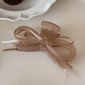 Macro view of amber hair claw clip with delicate ribbon bow on white table - Brown