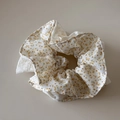 Detail van een stoffen scrunchie met gele bloemenprint op een witte getextureerde stof - Bloemen Scrunchie / Gele Getailleerde Stijl (FJ892934)