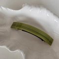 Dettaglio macro del fermaglio a molla in acetato verde curvo con logo di lusso inciso - Verde