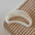 Macro view of creamy white acetate hair claw with marble texture on woven straw mat - White Glitter Jelly - Crescent