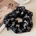 Détail d'un chouchou noir avec broderie nœud blanc et étiquette tissée de marque - Noir (Chouchou Standard)