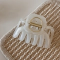 Detail of pearlescent cream hair claw clip with gold spring on a woven mat surface - White Glitter Jelly - Jellyfish Shape