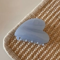Close-up of minimalist light blue hair claw clip with shimmer finish on woven texture - Glitter Jelly Blue - Heart Shape