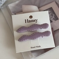 Detalle de dos pinzas para el cabello onduladas moradas con bordes cosidos blancos en tarjeta - Morado