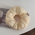 Detail view of a large yellow gingham scrunchie on a white table next to an open book - Yellow Plaid