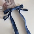 Detalle de lazo de tela vaquera azul con costuras marrones y cintas largas para el pelo - Azul claro