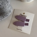 Dettaglio di fermagli in resina viola con cuciture beige su cartoncino da esposizione - Viola