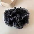 Close-up of black mesh scrunchie with plaid edge detail on a minimalist beige desk - Black