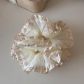 Macro shot of cream mesh scrunchie with brown gingham lace edges for ponytail styling - Beige