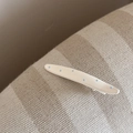 Gros plan d'une pince à cheveux blanche à pois bleu clair sur tissu beige - Droit (FJ892289) / Blanc