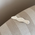 Gros plan d'une pince à cheveux blanche ondulée à pois bleu clair sur tissu - Vague (FJ892289) / Blanc