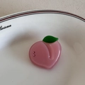 Dettaglio di una molletta per capelli a pesca in acetato con strass e foglia verde - Pesca