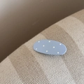 Gros plan d'une pince à cheveux mate bleu clair à pois blancs sur tissu rayé - Ovale (FJ892289) / Bleu