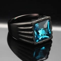 Macro di un anello da uomo in acciaio al titanio con gemma blu quadrata e motivi a onde - Base Nera Pietra Blu Aqua