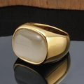 Gold wide band signet ring with a rectangular grey cat-eye stone on a black mirror surface - Gold White Stone
