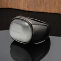 Detailed view of heavy gunmetal ring with oval cat's eye stone on reflective surface - Black White Stone